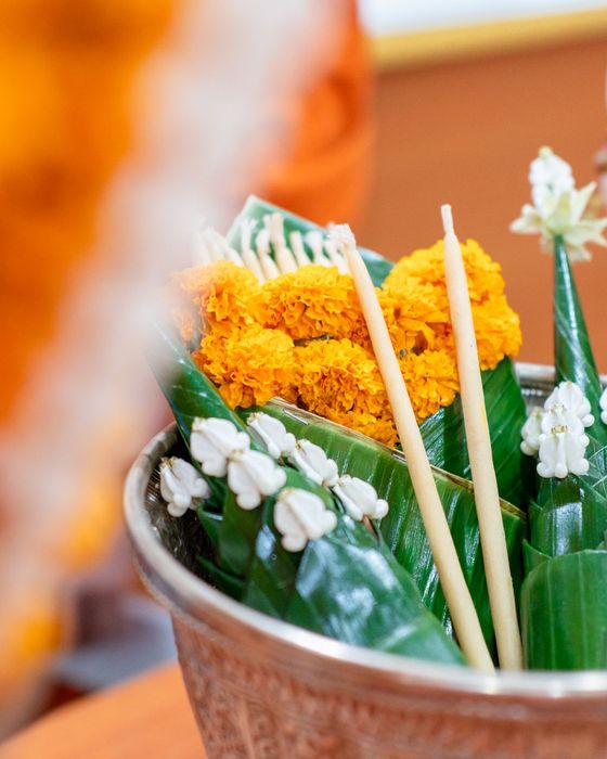 พานดอกดาวเรือง ดอกไม้สีขาว และธูปเทียนในขันเงิน